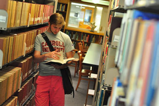 Image of a student in the library stacks with a book
