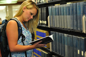 Image of a student looking at books in the stacks