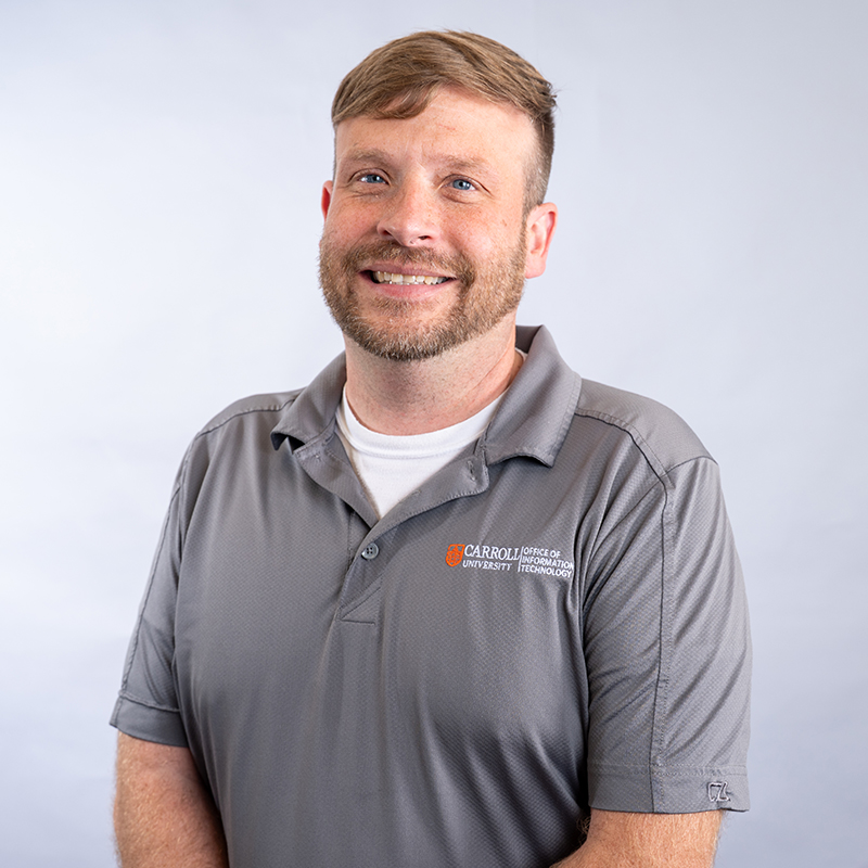 A person in a gray Carroll University Office of Information Technology polo shirt.