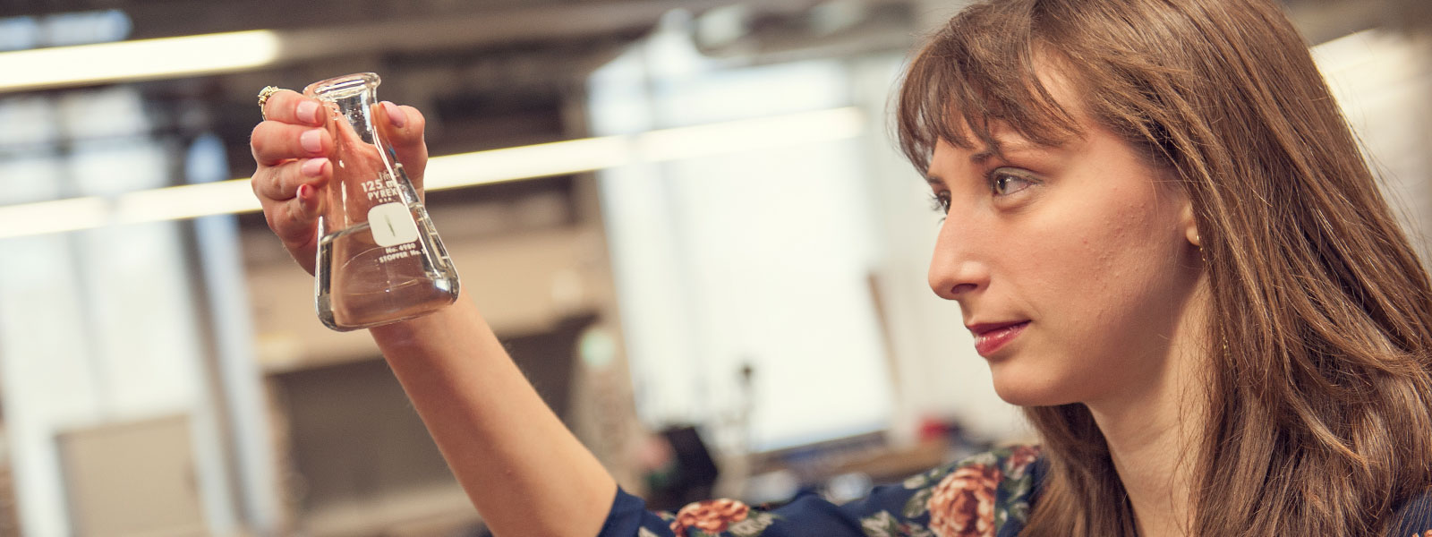 science student looking at liquid in a glass vessel