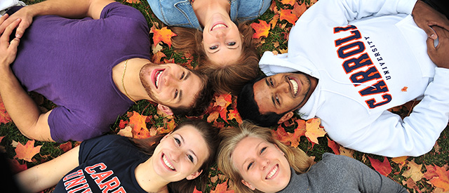 students in leaves smiling up at camera