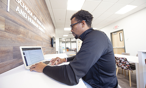 Student working on laptop in the school of education and human services building