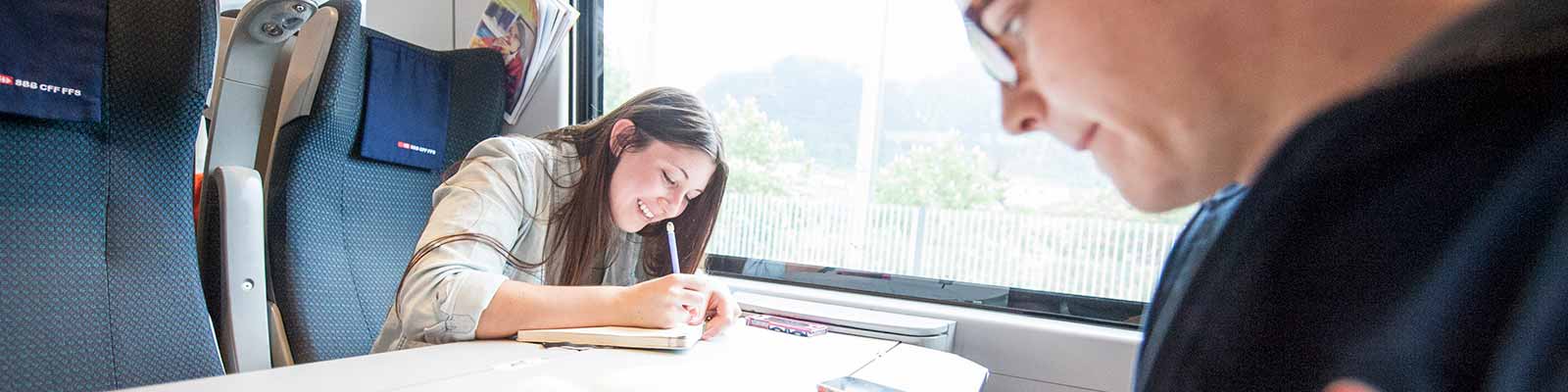 Female student writing while traveling on a train