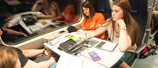 Female Carroll students writing while traveling on a train