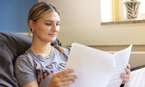 Student wearing Carroll University shirt reviewing papers
