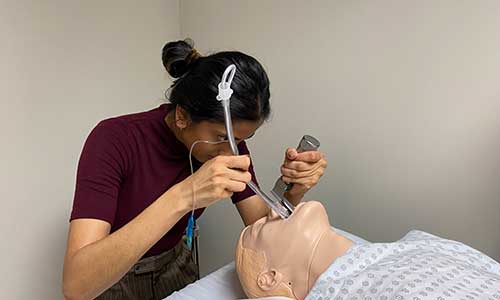 a woman practicing on a patient mannequin.