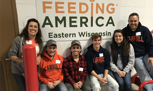 Carroll students sitting in front of Feeding America a sign.