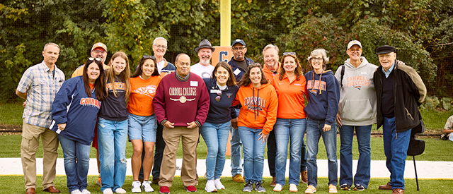 Alumni standing on the football field.