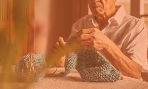 an older man knitting.
