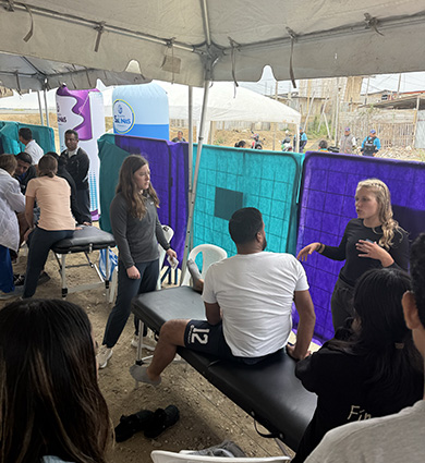 Carroll DPT Students speak with patients in tent in Ecuador