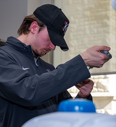 Carroll University male student fills tube in biology lab
