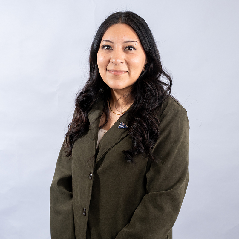 Women with brown hair in a dark green blazer.