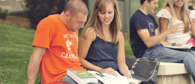 Carroll University students sitting reading a book together.