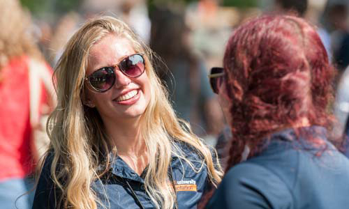 a Carroll University student wearing sunglasses smiling at another student.