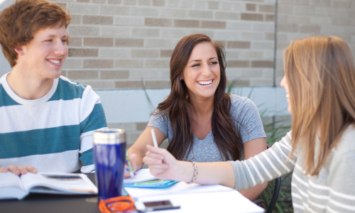 three students sharing a laugh while studying 