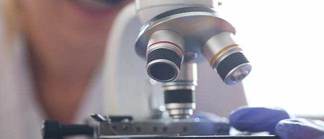 woman standing behind a microscope