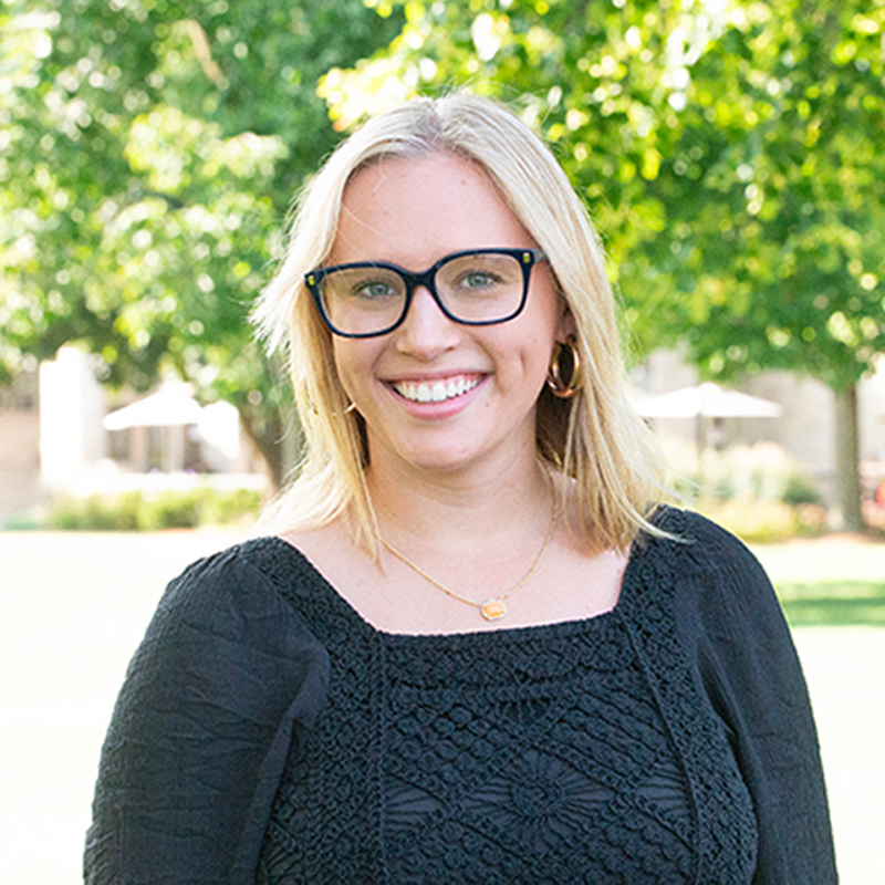 Women with blonde hair and glasses in a black blouse.