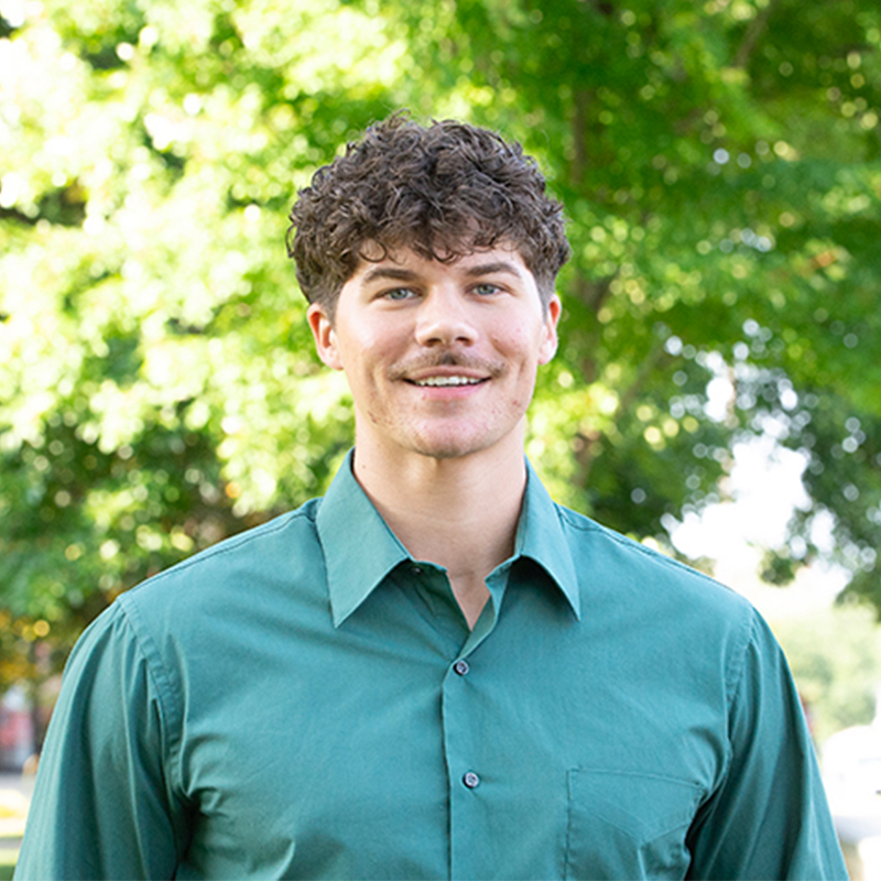 Man with brown curly hair and a green shirt.