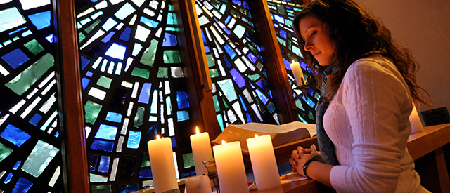 student looking at candles in chapel