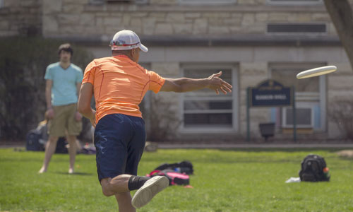 Students playing frisbee on the back quad