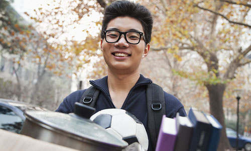 Student carrying a box of possessions as he moves into his dorm. 